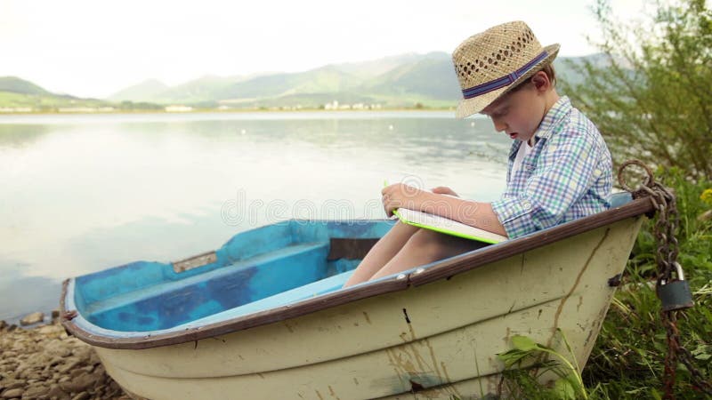 Menino que lê um livro interessante no barco velho