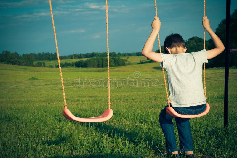 Menino só triste que senta-se no balanço foto de stock Menino só triste que senta-se no balanço foto de stock