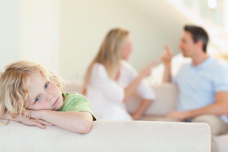 Menino triste com argumentação de pais atrás dele fotos de stock