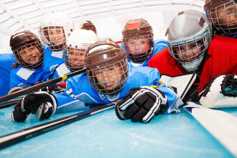 Meninos felizes no uniforme do hóquei que coloca na pista de gelo fotografia de stock Meninos felizes no uniforme do hóquei que coloca na pista de gelo fotografia de stock