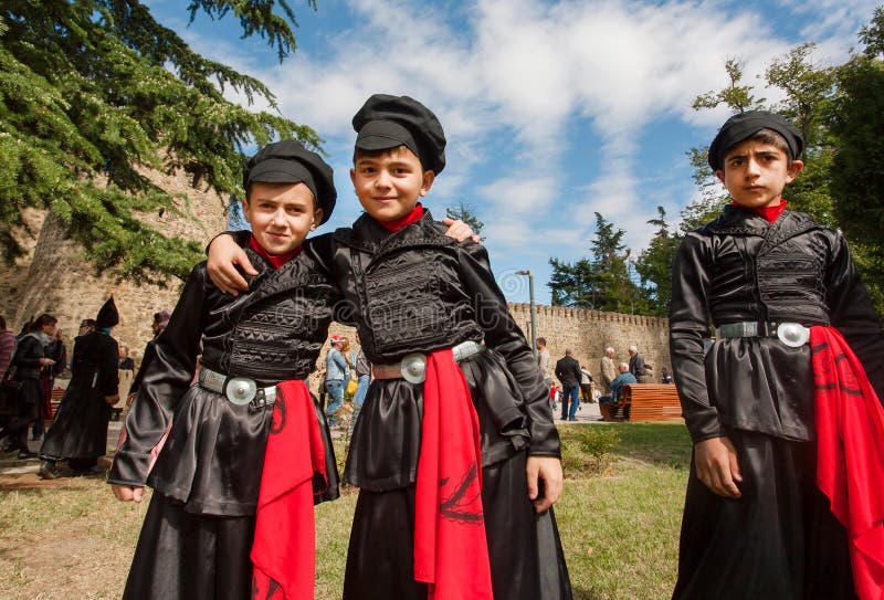 Meninos nos trajes Georgian da forma velha que abraçam como melhores amigos na multidão de festival da rua