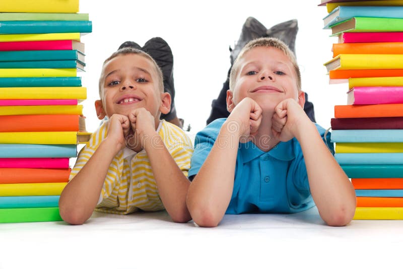 Meninos que encontram-se entre os livros fotos de stock Meninos que encontram-se entre os livros fotos de stock