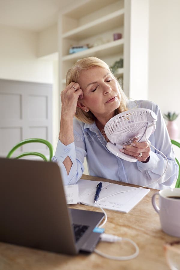 Menopausal Mature Woman Having Hot Flush At Home Cooling Herself With