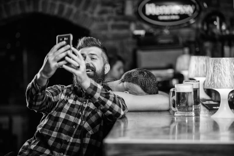 Mens in bar het drinken bier Neem selfie foto om grote avond in bar te herinneren De greepsmartphone van mensen gebaarde hipster stock afbeeldingen Mens in bar het drinken bier Neem selfie foto om grote avond in bar te herinneren De greepsmartphone van mensen gebaarde hipster stock afbeeldingen