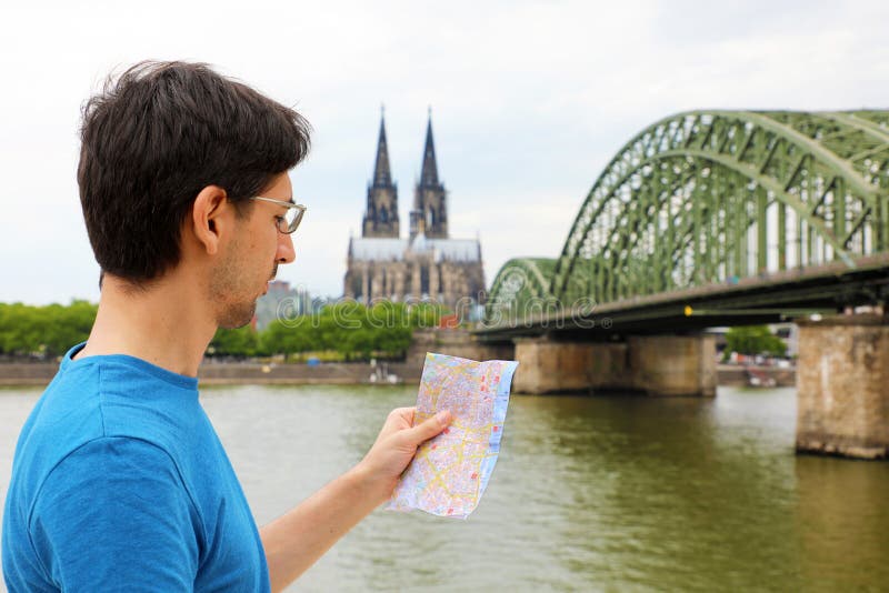 Mens die aan zijn document kaart in zijn hand met de Kathedraal van Keulen en brug op Rijn-rivier, Duitsland kijken Reis in Europ royalty-vrije stock foto Mens die aan zijn document kaart in zijn hand met de Kathedraal van Keulen en brug op Rijn-rivier, Duitsland kijken Reis in Europ royalty-vrije stock foto