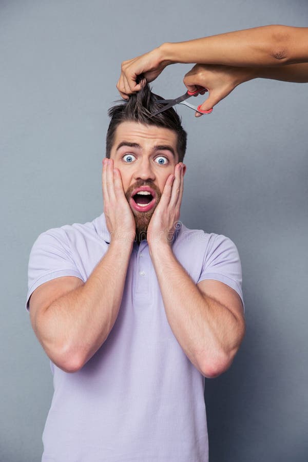 Mens die bang gemaakt terwijl vrouwelijke handen die zijn haar snijden kijken royalty-vrije stock afbeeldingen Mens die bang gemaakt terwijl vrouwelijke handen die zijn haar snijden kijken royalty-vrije stock afbeeldingen