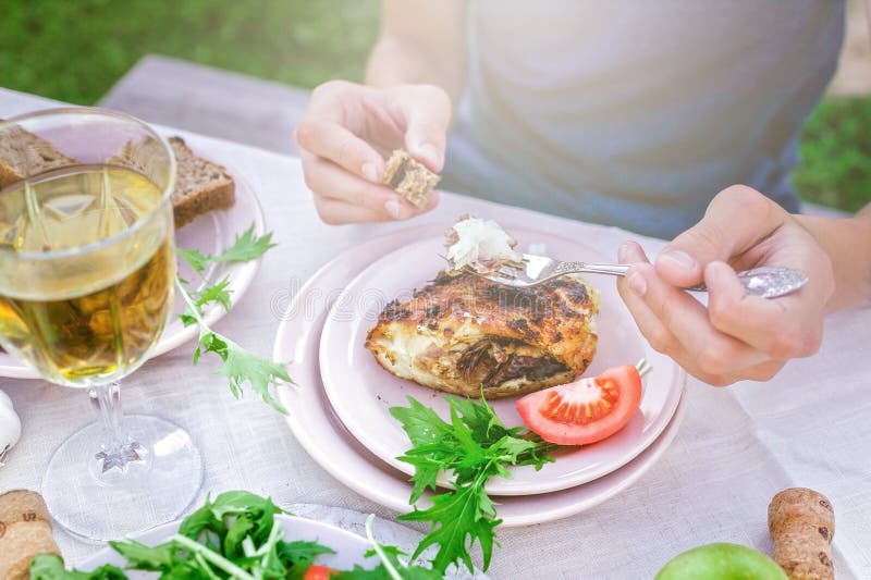 Man eating fried sea fish in the garden at the table. Dinner concept with wine in the fresh air. Fish and salads with vegetables and herbs. Mediterranean Kitchen. Horizontal shot. Man eating fried sea fish in the garden at the table. Dinner concept with wine in the fresh air. Fish and salads with vegetables and herbs. Mediterranean Kitchen. Horizontal shot