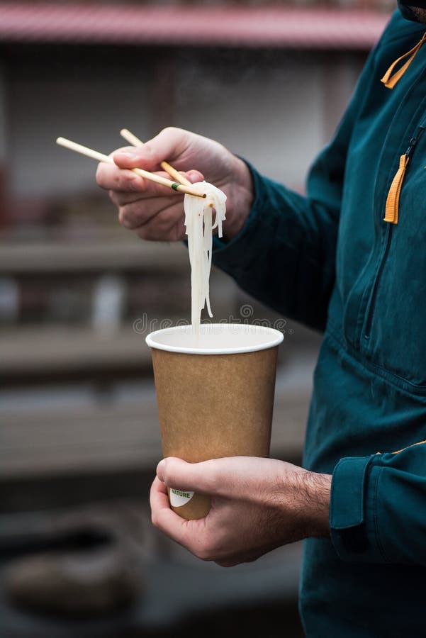 Mens die heet Vietnamees voedsel in een biologisch afbreekbare kop eten stock afbeeldingen Mens die heet Vietnamees voedsel in een biologisch afbreekbare kop eten stock afbeeldingen