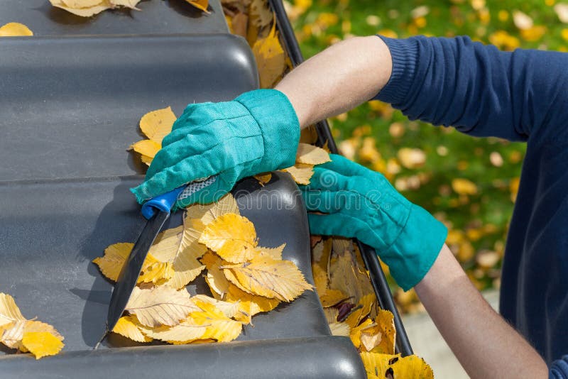 Mens die het dak in de herfst schoonmaken stock foto Mens die het dak in de herfst schoonmaken stock foto
