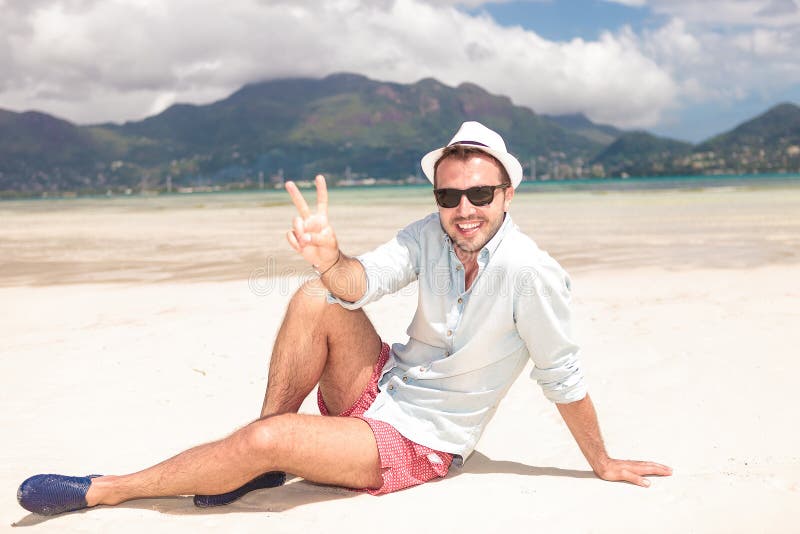 Mens die het teken van de overwinningsvrede op het strand maken royalty-vrije stock foto's Mens die het teken van de overwinningsvrede op het strand maken royalty-vrije stock foto's