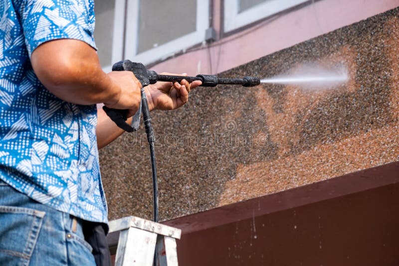 Mens die het Water die van de Hoge Machtsdruk voor Ineenstorting gebruiken Vuile Wal schoonmaken royalty-vrije stock afbeelding Mens die het Water die van de Hoge Machtsdruk voor Ineenstorting gebruiken Vuile Wal schoonmaken royalty-vrije stock afbeelding
