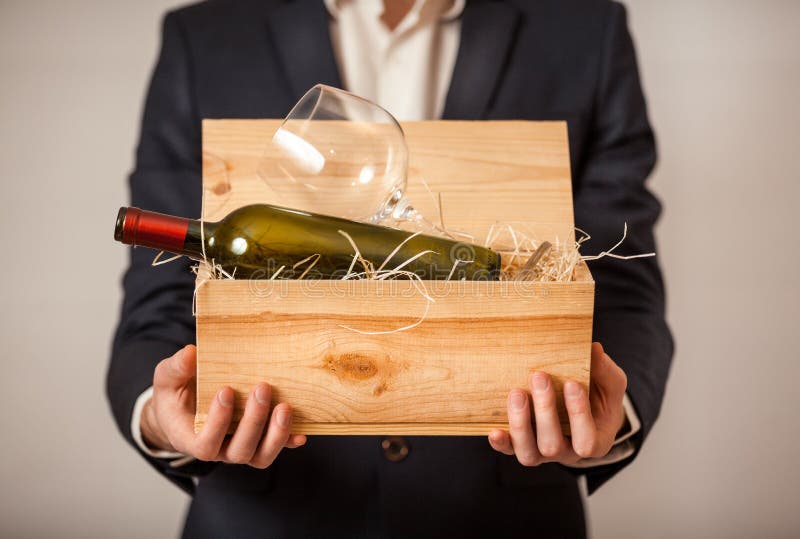 Mens die in jasje open doos met fles wijn houden stock afbeeldingen Mens die in jasje open doos met fles wijn houden stock afbeeldingen