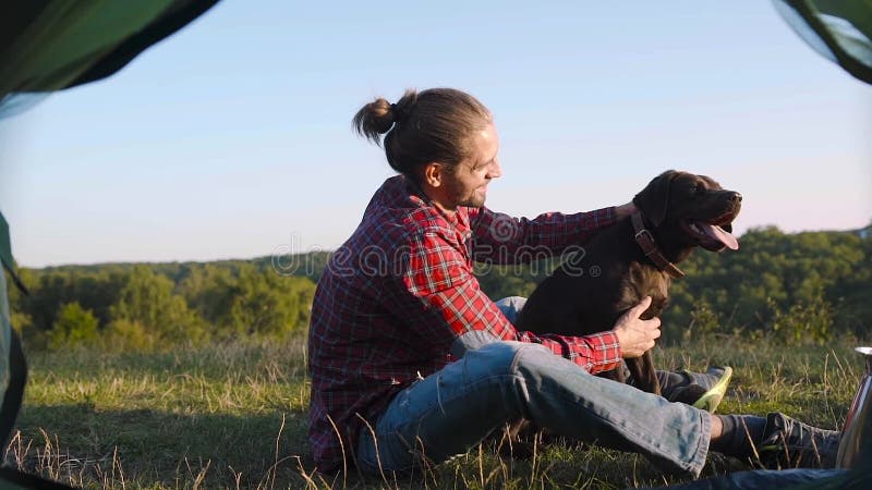 Mens die met hond reizen, die in aard kamperen