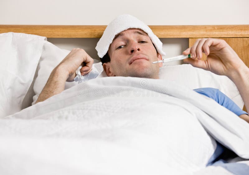 Mens die met koorts in bed legt dat temperatuur vergt royalty-vrije stock foto's Mens die met koorts in bed legt dat temperatuur vergt royalty-vrije stock foto's