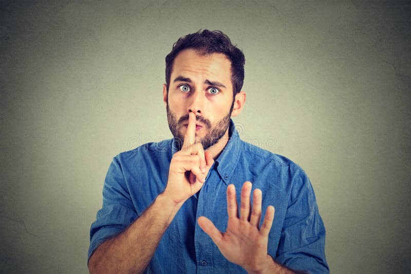 Young handsome man giving Shhhh quiet, silence, secret gesture on gray wall background. Young handsome man giving Shhhh quiet, silence, secret gesture on gray wall background