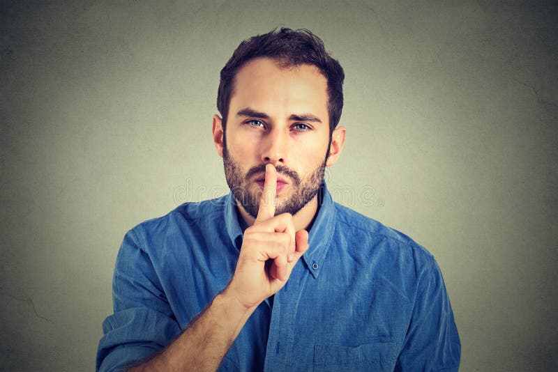 Young handsome man giving Shhhh quiet, silence, secret gesture on gray wall background. Young handsome man giving Shhhh quiet, silence, secret gesture on gray wall background