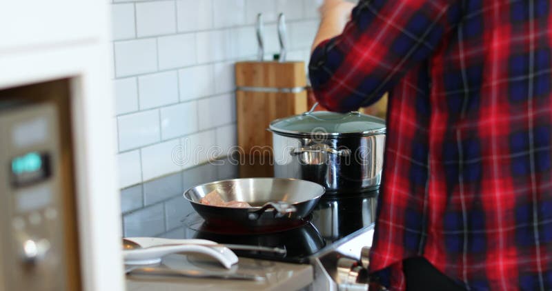 Mens die vleesstukken in pan in keuken 4k houden