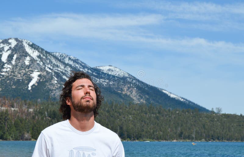 Mens die in vrede in Meer Tahoe, Californië ademen Sneeuwbergen op de achtergrond royalty-vrije stock fotografie Mens die in vrede in Meer Tahoe, Californië ademen Sneeuwbergen op de achtergrond royalty-vrije stock fotografie