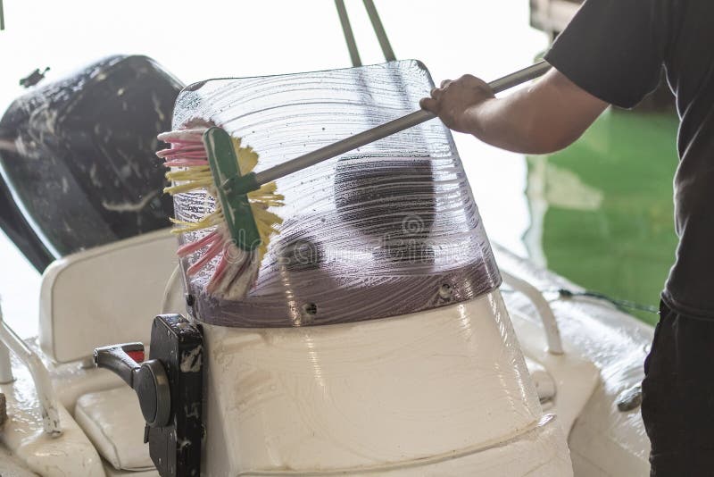 Mens die witte opblaasbare boot met borstel en het systeem van het drukwater wassen bij garage De schipdienst en seizoengebonden stock afbeelding Mens die witte opblaasbare boot met borstel en het systeem van het drukwater wassen bij garage De schipdienst en seizoengebonden stock afbeelding