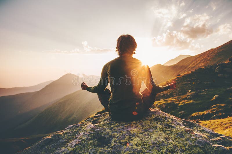 Mens die yoga mediteren bij zonsondergangbergen