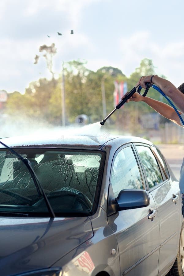 Mens die zijn auto wassen onder hoge drukwater royalty-vrije stock fotografie Mens die zijn auto wassen onder hoge drukwater royalty-vrije stock fotografie