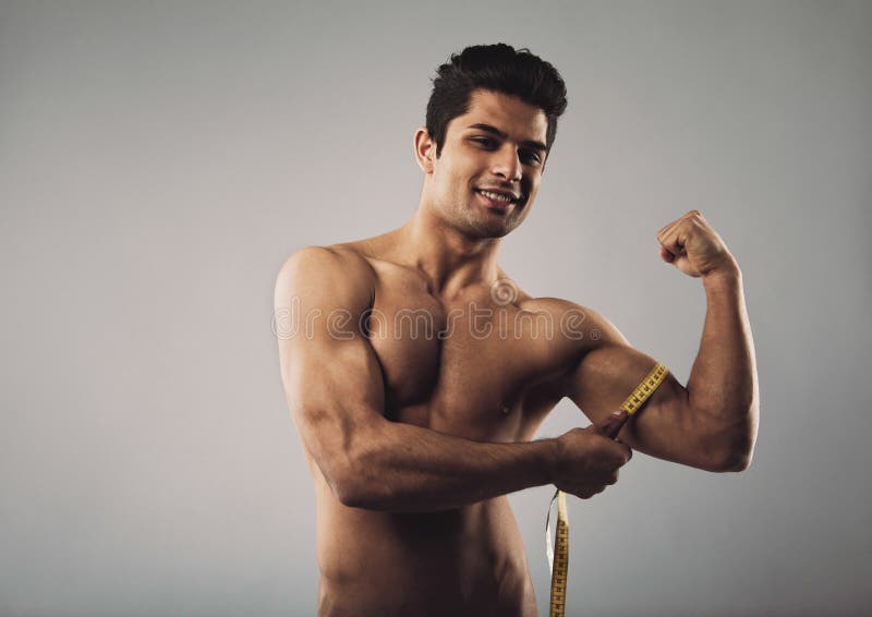 Mens die zijn bicepsen met een meetlint meten stock fotografie Mens die zijn bicepsen met een meetlint meten stock fotografie