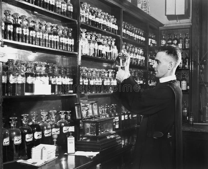 Mens in een apotheek die geneeskunde mengen (Alle afgeschilderde personen leven niet langer en geen landgoed bestaat Leveranciers stock foto's Mens in een apotheek die geneeskunde mengen (Alle afgeschilderde personen leven niet langer en geen landgoed bestaat Leveranciers stock foto's