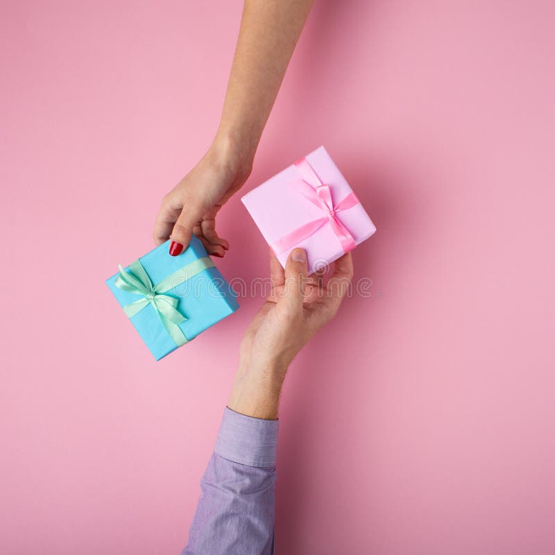 Mens en meisje die giften van hand aan hand ruilen, vakjes die in decoratief document met een boog op pastelkleurachtergrond word stock afbeeldingen Mens en meisje die giften van hand aan hand ruilen, vakjes die in decoratief document met een boog op pastelkleurachtergrond word stock afbeeldingen