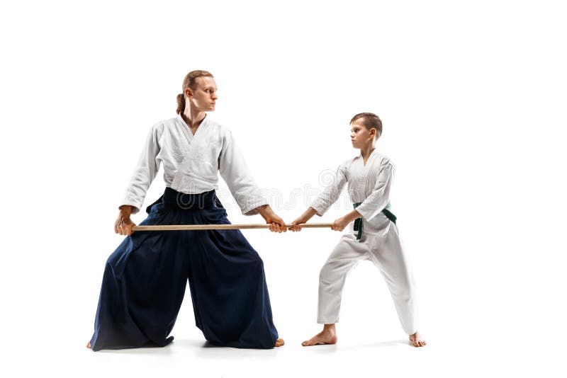 Mens en tienerjongen het vechten met houten zwaarden bij Aikido-opleiding in vechtsportenschool royalty-vrije stock fotografie Mens en tienerjongen het vechten met houten zwaarden bij Aikido-opleiding in vechtsportenschool royalty-vrije stock fotografie