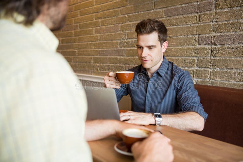 Mens en Vriend in Koffiewinkel die Computer met behulp van royalty-vrije stock afbeeldingen Mens en Vriend in Koffiewinkel die Computer met behulp van royalty-vrije stock afbeeldingen