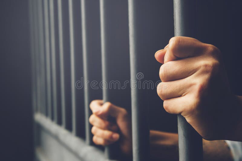 Mens in gevangenishanden van de achter bars van de de kooigevangenis van het greepstaal