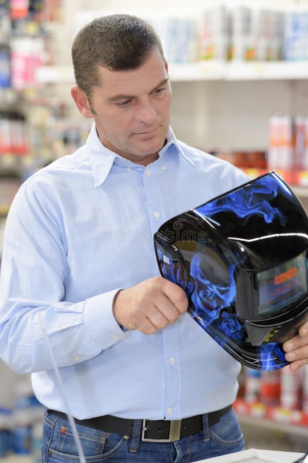 Mens het kopen lassenmasker in ijzerhandel stock afbeelding Mens het kopen lassenmasker in ijzerhandel stock afbeelding