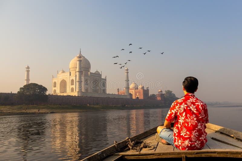 Mens het letten op zonsondergang over Taj Mahal van een houten boot met vogel die over vliegen stock afbeelding Mens het letten op zonsondergang over Taj Mahal van een houten boot met vogel die over vliegen stock afbeelding