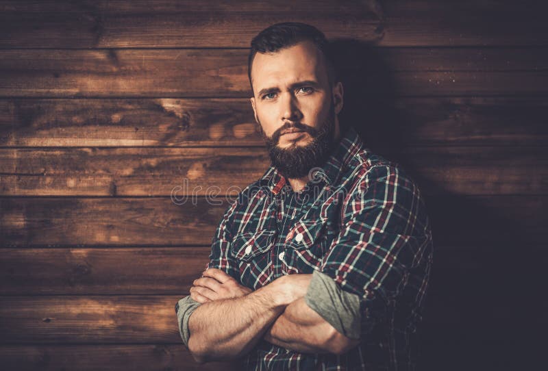 Handsome man wearing checkered shirt in wooden rural house interior. Handsome man wearing checkered shirt in wooden rural house interior