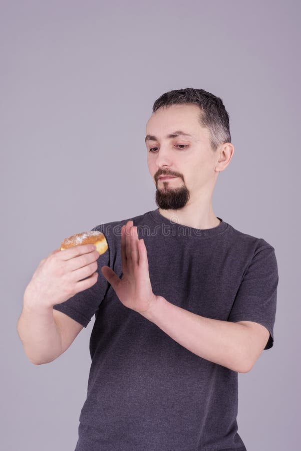 Mens met een baard die een broodje over grijze achtergrond eten stock afbeelding Mens met een baard die een broodje over grijze achtergrond eten stock afbeelding