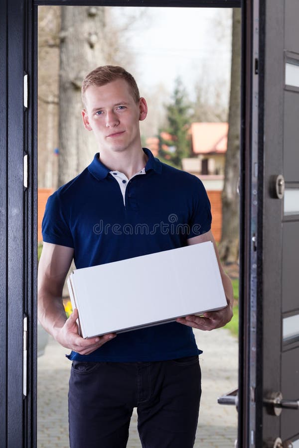 A young adult standing in at the door with a package. A young adult standing in at the door with a package