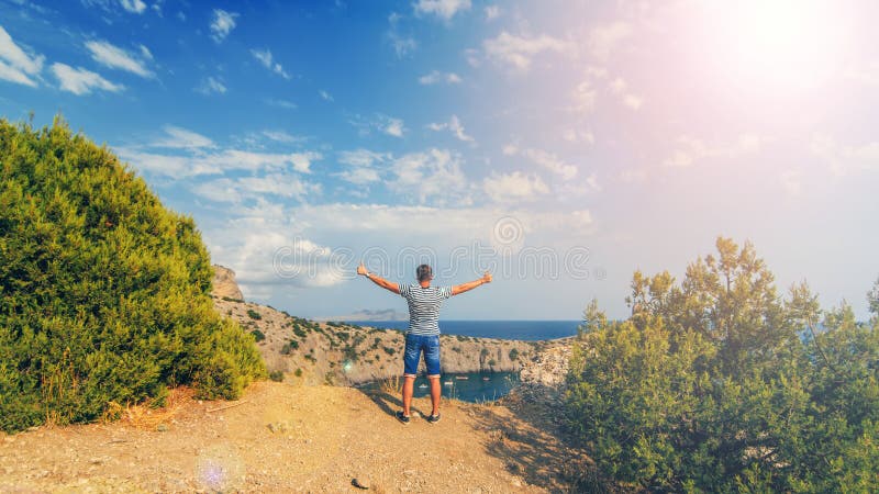 Mens met handen in de zomer op de achtergrond van het overzees op de bovenkant van de bergen in openlucht worden opgeheven die stock foto Mens met handen in de zomer op de achtergrond van het overzees op de bovenkant van de bergen in openlucht worden opgeheven die stock foto