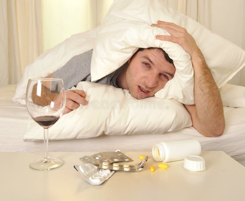 Mens met hoofdpijn en kater in bed met tabletten royalty-vrije stock fotografie Mens met hoofdpijn en kater in bed met tabletten royalty-vrije stock fotografie