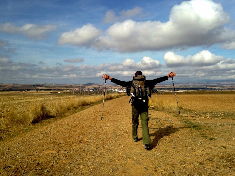 Mens met rugzak het uitspreiden wapens en het lopen op gebied Caminode Santiago concept Bedevaartconcept royalty-vrije stock afbeelding Mens met rugzak het uitspreiden wapens en het lopen op gebied Caminode Santiago concept Bedevaartconcept royalty-vrije stock afbeelding