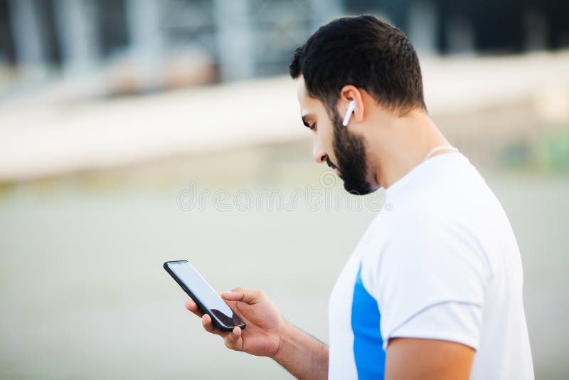 Mens na het uitwerken in het stadspark en het gebruiken van zijn mobiele telefoon stock foto's Mens na het uitwerken in het stadspark en het gebruiken van zijn mobiele telefoon stock foto's