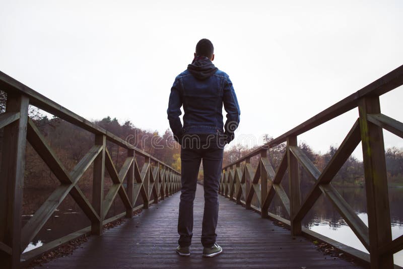Mens op houten brug over een meer, op een vochtige de herfstdag royalty-vrije stock afbeelding Mens op houten brug over een meer, op een vochtige de herfstdag royalty-vrije stock afbeelding