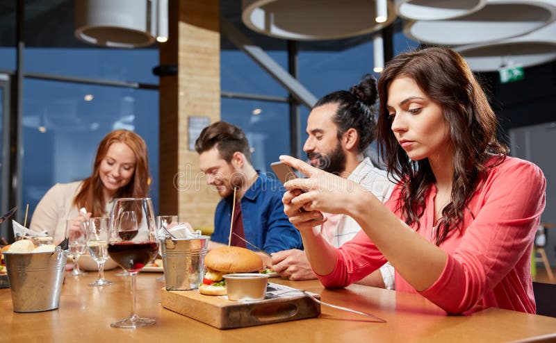 Mensajería agujereada de la mujer en smartphone en el restaurante imágenes de archivo libres de regalías Mensajería agujereada de la mujer en smartphone en el restaurante imágenes de archivo libres de regalías