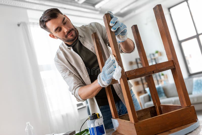 renovation, diy and home improvement concept - man degreasing old round wooden table surface with tissue. renovation, diy and home improvement concept - man degreasing old round wooden table surface with tissue