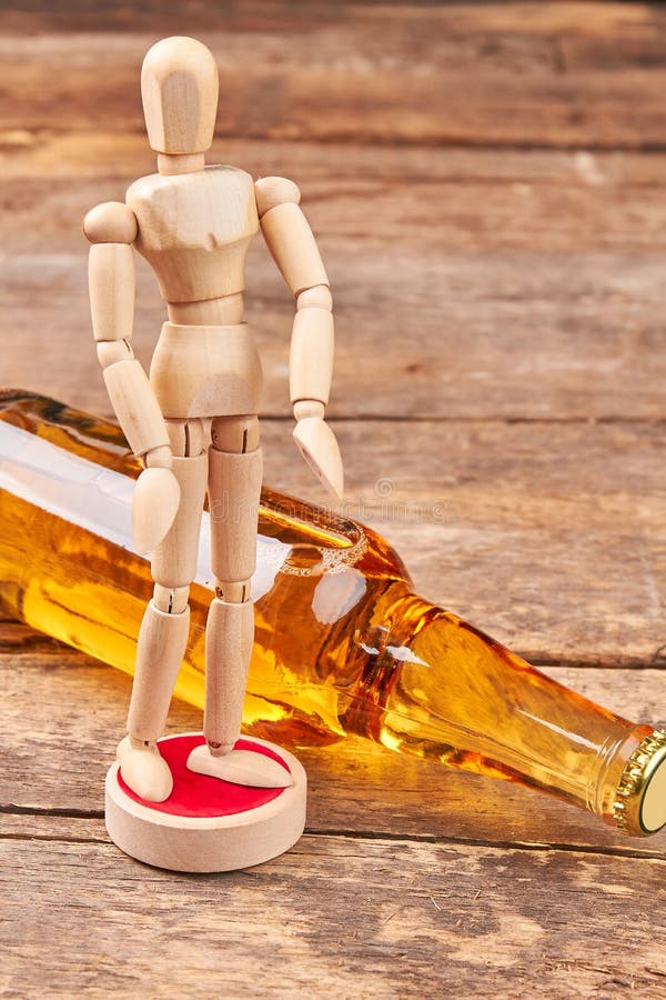 Menselijk houten model, fles alcohol royalty-vrije stock afbeelding Menselijk houten model, fles alcohol royalty-vrije stock afbeelding