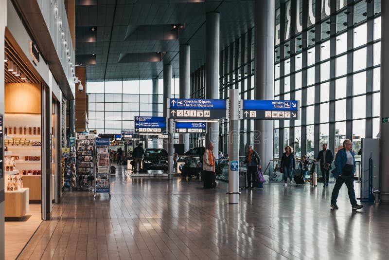Mensen die langs richtingaanwijzers lopen in de terminal van de luchthaven van Luxemburg stock fotografie Mensen die langs richtingaanwijzers lopen in de terminal van de luchthaven van Luxemburg stock fotografie