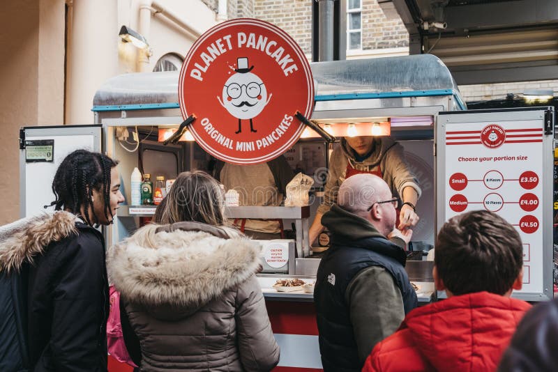 Mensen die minipannekoeken kopen van een tribune van de Planeetpannekoek bij de Markt van Greenwich, Londen, het UK stock fotografie Mensen die minipannekoeken kopen van een tribune van de Planeetpannekoek bij de Markt van Greenwich, Londen, het UK stock fotografie