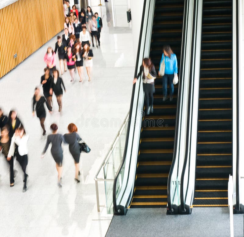 People rushing on escalator in business center, mall or airport to work, with motion blur . People rushing on escalator in business center, mall or airport to work, with motion blur .