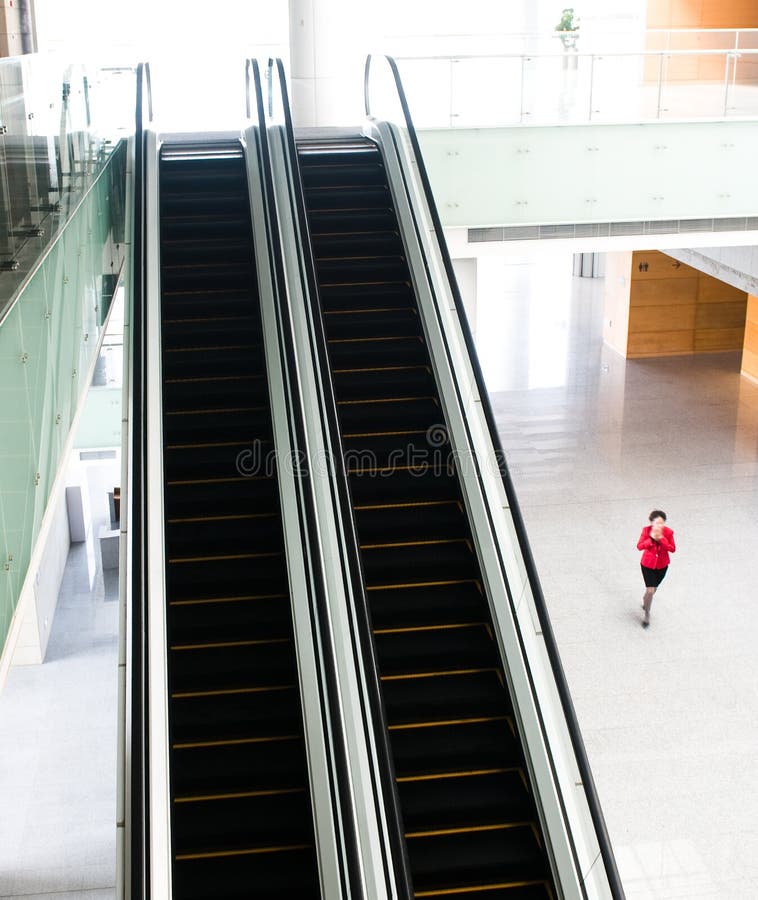 People rushing on escalator in business center, mall or airport to work, with motion blur . People rushing on escalator in business center, mall or airport to work, with motion blur .