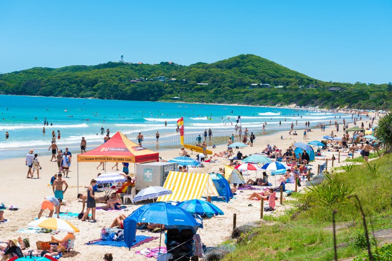 Byron Bay, NSW, Australia- January 3, 2018: People enjoying the sunny weather on the beach at Byron Bay, a popular destination with beaches and coastal trails on the North Coast of NSW, Australia. Byron Bay, NSW, Australia- January 3, 2018: People enjoying the sunny weather on the beach at Byron Bay, a popular destination with beaches and coastal trails on the North Coast of NSW, Australia.