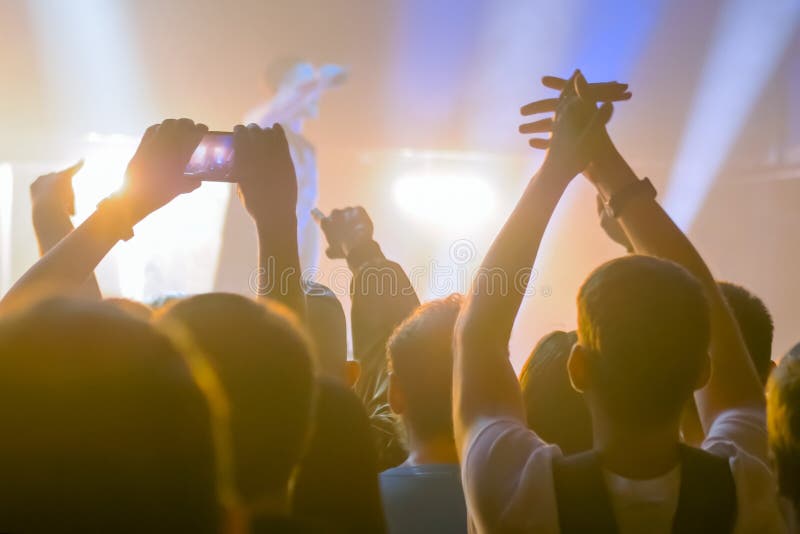 People hands silhouette taking photo or recording video of live music concert with smartphone. Crowd partying in front of stage. Photography, entertainment, technology concept. People hands silhouette taking photo or recording video of live music concert with smartphone. Crowd partying in front of stage. Photography, entertainment, technology concept